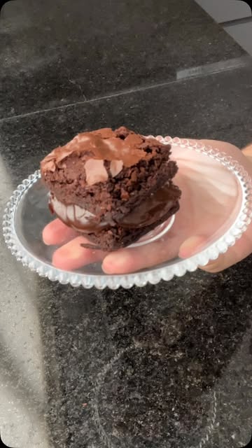 Brownie recheado com creme branco servido em um pratinho de vidro